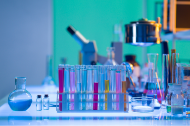 Vue d'un laboratoire R&D avec tubes à essai multicolores, verrerie de précision et équipements analytiques, représentant un espace de travail structuré et digitalisable via une solution ELN/LIMS comme Laby.