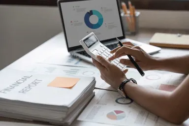 Une personne qui fait la comptabilité avec une calculatrice à la main.