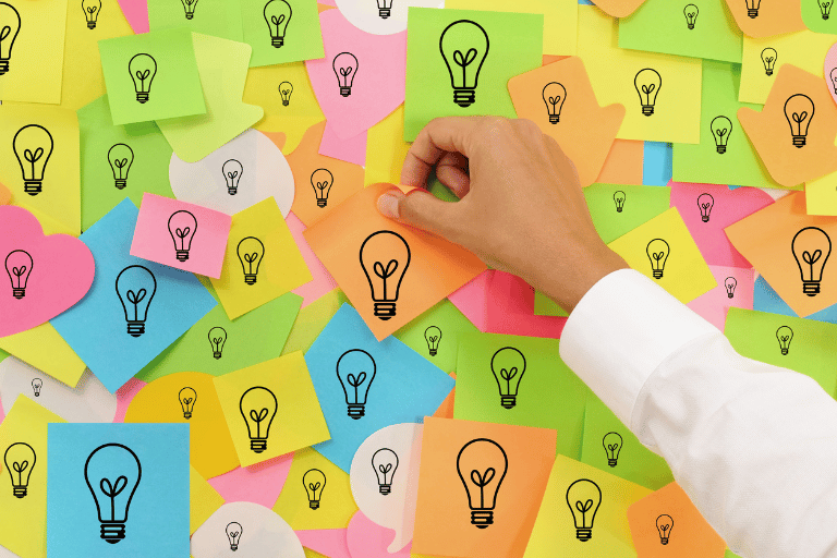 Wall of colorful post-it notes with light bulbs, illustrating the abundance of ideas in the laboratory but also the lack of digitalization and organization to exploit them.