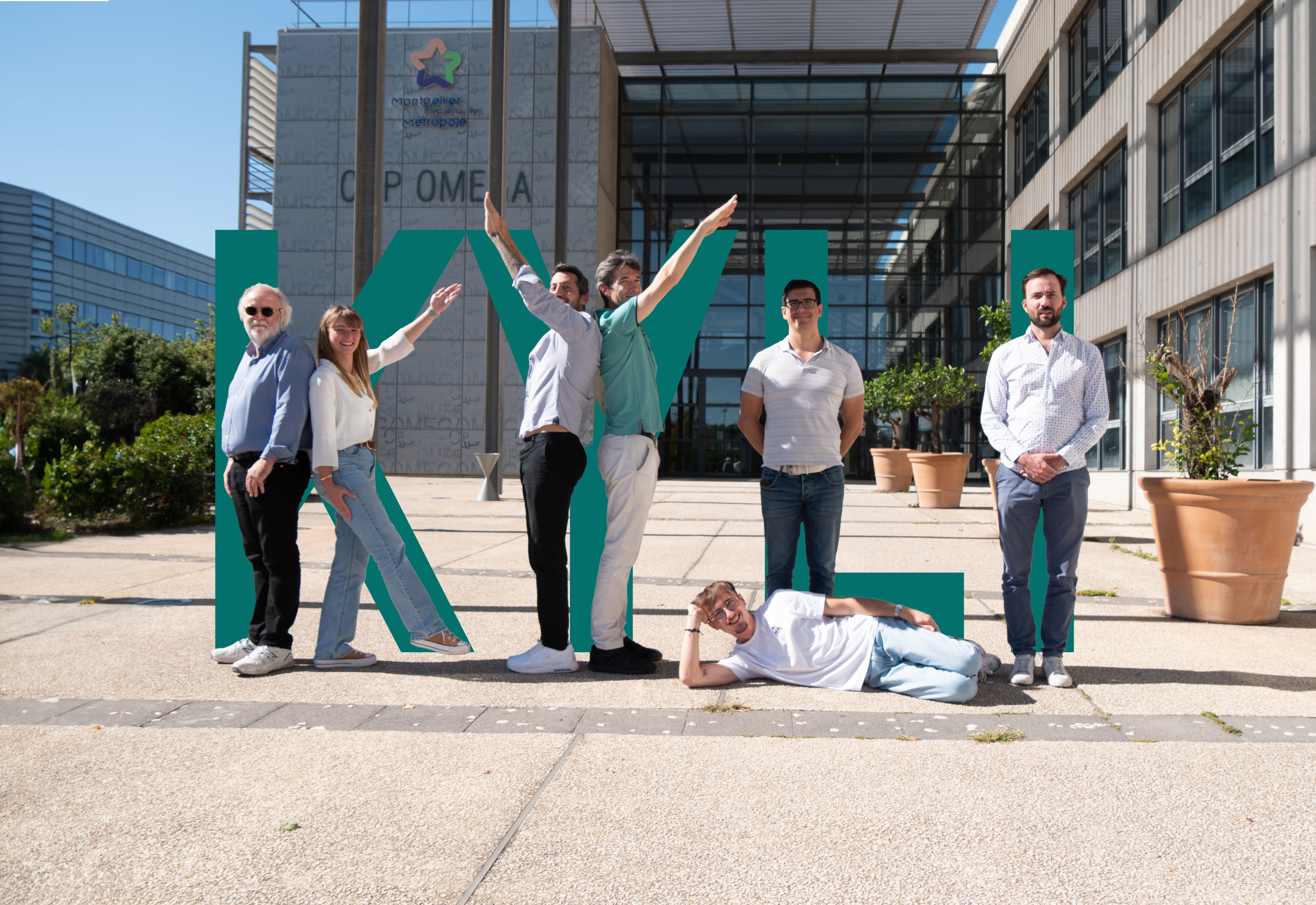 Photo of the team of 10 employees outside the building. They are in fun and different poses.