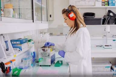 Femme en blouse blanche testant des échantillons à l'aide d'équipements dans un laboratoire.